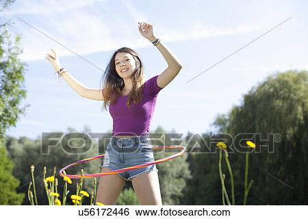 Stock Photograph - Teenage girl hoola hooping in park. Fotosearch
