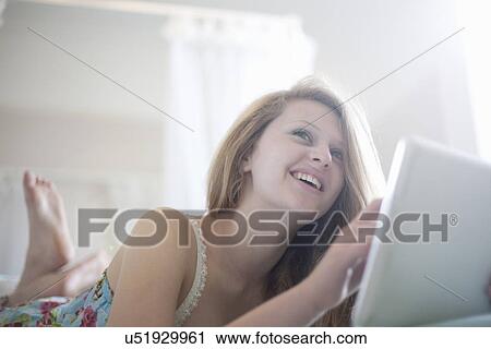 Teenage girl relaxing on bed with digital tablet View Large Photo Image Stock Image - Teenage girl relaxing on bed with digital tablet. Fotosearch