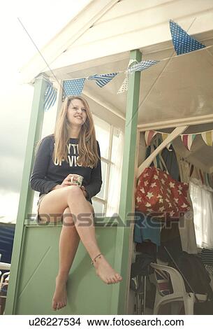 Picture - Teenage girl sitting on beach hut porch, Southwold, Sussex, UK. Fotosearch