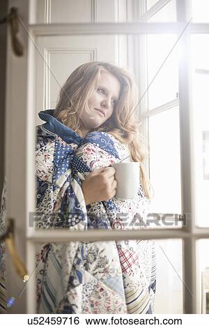Stock Photograph - Teenage girl wrapped in a blanket holding a coffee mug. Fotosearch