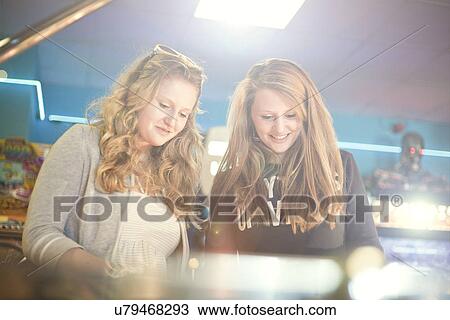 Teenage girls playing games in amusement arcade View Large Photo Image Stock Image - Teenage girls playing games in amusement arcade. Fotosearch