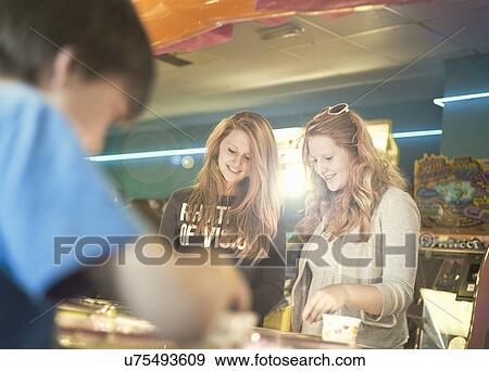 Teenage sisters playing games in amusement arcade View Large Photo Image Stock Photo - Teenage sisters playing games in amusement arcade. Fotosearch