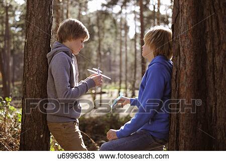 Twin brothers holding toy airplanes chatting in forest View Large Photo Image Stock Image - Twin brothers holding toy airplanes chatting in forest. Fotosearch
