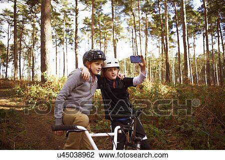 Stock Image - Twin brothers on BMX bikes taking self portrait. Fotosearch