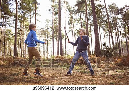 Twin brothers play fighting with sticks in forest View Large Photo Image Stock Image - Twin brothers play fighting with sticks in forest. Fotosearch