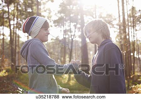 Twin brothers shaking hands on deal in forest View Large Photo Image Stock Photo - Twin brothers shaking hands on deal in forest. Fotosearch