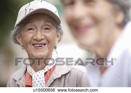 Stock Photograph - Two senior women talking in retirement villa garden. Fotosearch