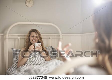Two teenage sisters chatting face to face in bed View Large Photo Image Stock Photography - Two teenage sisters chatting face to face in bed. Fotosearch