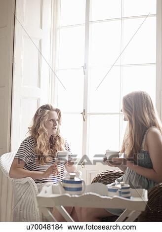 Two teenage sisters enjoying afternoon tea View Large Photo Image Picture - Two teenage sisters enjoying afternoon tea. Fotosearch