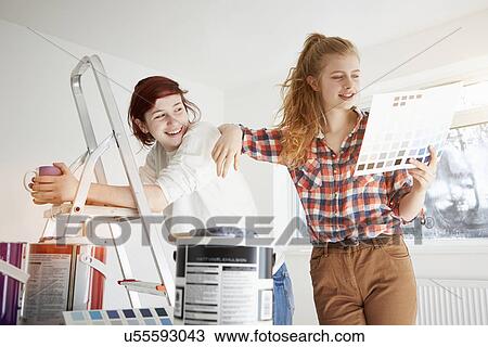 Stock Image - Two teenage sisters preparing to decorate bedroom. Fotosearch