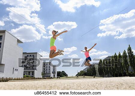 Stock Image - Two young women doing jump exercises. Fotosearch