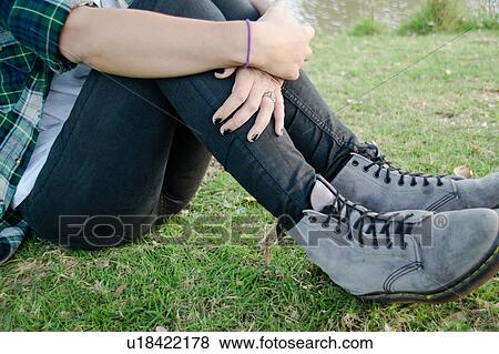 Stock Photo - Waist down, young woman sitting on grass. Fotosearch