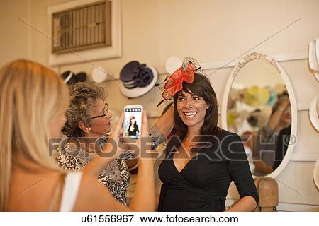 Stock Photo - Woman being photographed in traditional milliners shop. Fotosearch