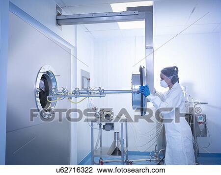 Stock Image - Worker inserting spray jets into tablet coating machine in pharmaceutical factory. Fotosearch