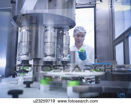 Stock Photo - Worker inspecting products on production line in pharmaceutical factory. Fotosearch