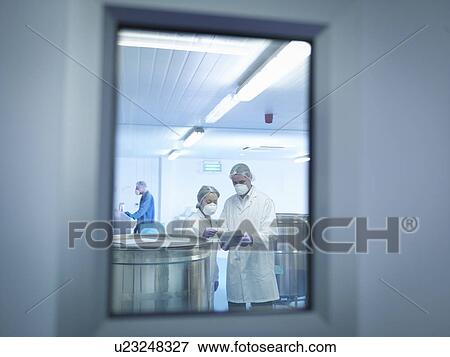 Stock Photo - Workers using digital tablet in pharmaceutical factory. Fotosearch