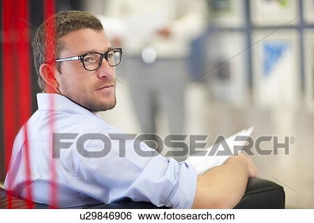 Young businessman sitting in office with paperwork View Large Photo Image Stock Photograph - Young businessman sitting in office with paperwork. Fotosearch