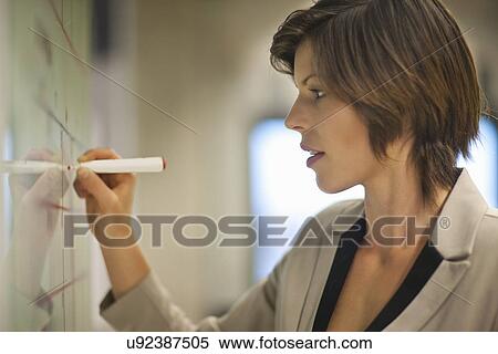 Stock Photography - Young businesswoman organizing timetables in office. Fotosearch