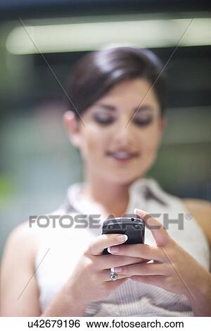 Young businesswoman texting on cellphone in office View Large Photo Image Stock Photograph - Young businesswoman texting on cellphone in office. Fotosearch
