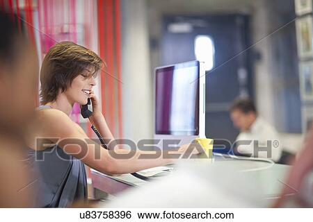 Young businesswoman using telephone in office View Large Photo Image Stock Photograph - Young businesswoman using telephone in office. Fotosearch