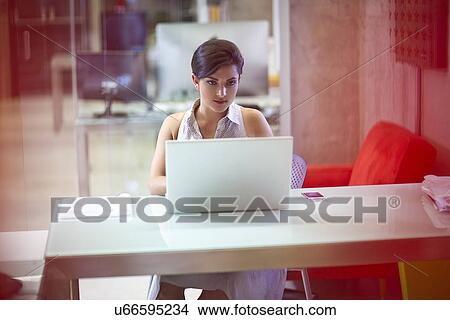 Young businesswoman working on laptop in office View Large Photo Image Picture - Young businesswoman working on laptop in office. Fotosearch