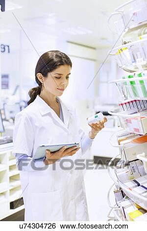 Young female pharmacist stock taking in pharmacy View Large Photo Image Stock Photograph - Young female pharmacist stock taking in pharmacy. Fotosearch