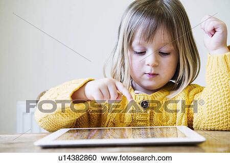 Young girl at kitchen table using digital tablet View Large Photo Image Stock Image - Young girl at kitchen table using digital tablet. Fotosearch