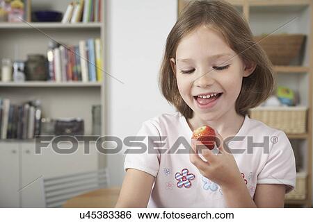Young girl in kitchen holding a fresh strawberry View Large Photo Image Stock Photograph - Young girl in kitchen holding a fresh strawberry. Fotosearch