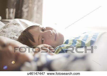 Stock Photo - Young girl lying on bed with her older brother. Fotosearch