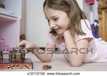 Young girl lying on bedroom floor playing with chess set View Large Photo Image Stock Image - Young girl lying on bedroom floor playing with chess set. Fotosearch