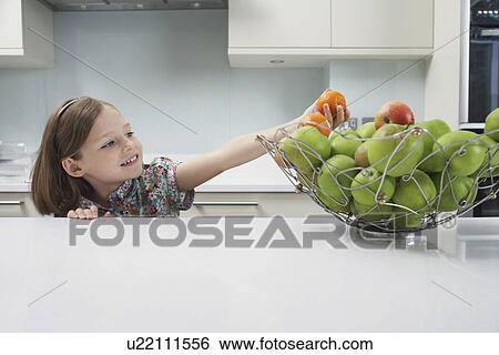 Young girl reaching for a tangerine from the fruit bowl View Large Photo Image Stock Photograph - Young girl reaching for a tangerine from the fruit bowl. Fotosearch