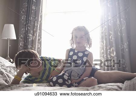 Young girl sitting on bed with her older brother View Large Photo Image Stock Image - Young girl sitting on bed with her older brother. Fotosearch
