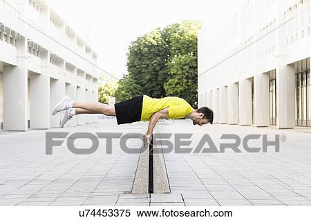 Stock Photography - Young man balancing horizontally on divider. Fotosearch