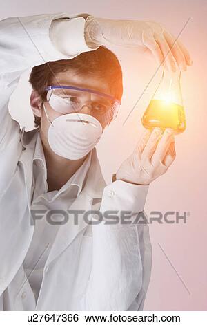 Young scientist holding golden liquid in flask View Large Photo Image Stock Photograph - Young scientist holding golden liquid in flask. Fotosearch