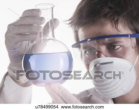 Young scientist looking at liquid in flask View Large Photo Image Picture - Young scientist looking at liquid in flask. Fotosearch