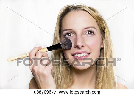 Stock Photo - Young woman applying blusher. Fotosearch