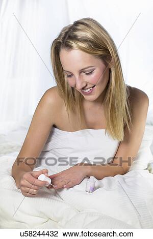 Stock Image - Young woman applying nail varnish. Fotosearch