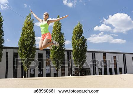 Young woman doing jump exercises in park View Large Photo Image Stock Image - Young woman doing jump exercises in park. Fotosearch