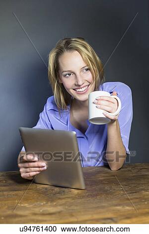 Stock Image - Young woman drinking coffee and digital tablet. Fotosearch