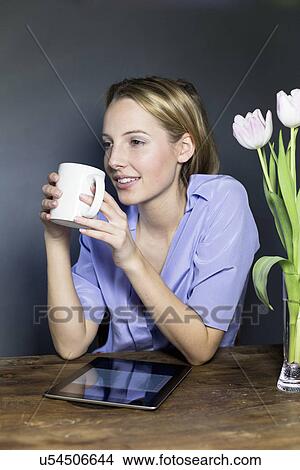 Picture - Young woman drinking coffee with digital tablet. Fotosearch