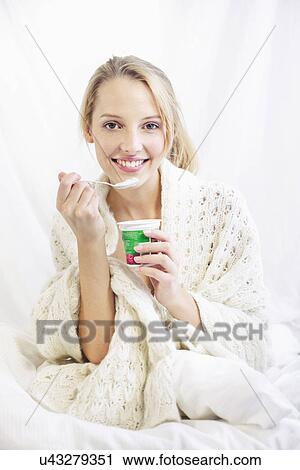 Young woman eating yoghurt, smiling View Large Photo Image Stock Image - Young woman eating yoghurt, smiling. Fotosearch