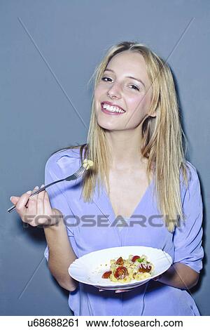 Stock Image - Young woman holding plate of food. Fotosearch