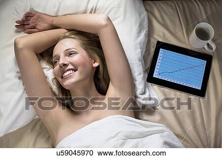 Young woman lying in bed with digital tablet View Large Photo Image Stock Image - Young woman lying in bed with digital tablet. Fotosearch