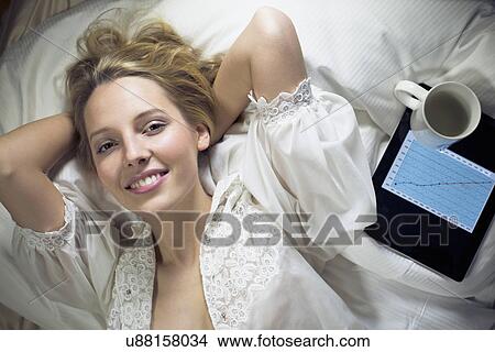 Young woman lying on bed with digital tablet View Large Photo Image Picture - Young woman lying on bed with digital tablet. Fotosearch