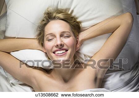 Young woman lying on bed with hands behind head View Large Photo Image Stock Image - Young woman lying on bed with hands behind head. Fotosearch