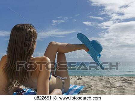 Young woman relaxing on beach with blue sunhat View Large Photo Image Stock Photo - Young woman relaxing on beach with blue sunhat. Fotosearch