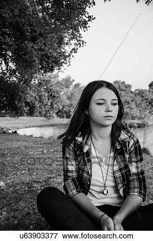 Stock Photo - Young woman sitting on grass. Fotosearch