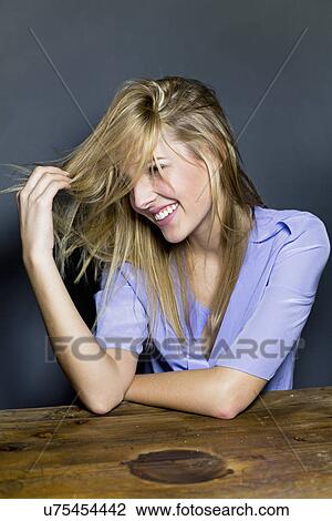 Stock Image - Young woman touching hair. Fotosearch