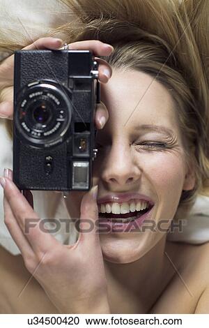Stock Image - Young woman using vintage camera. Fotosearch