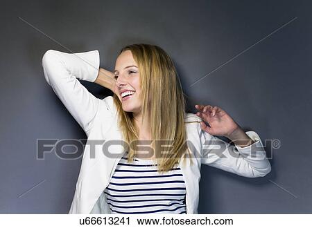 Stock Image - Young woman wearing striped top with hand in hair. Fotosearch
